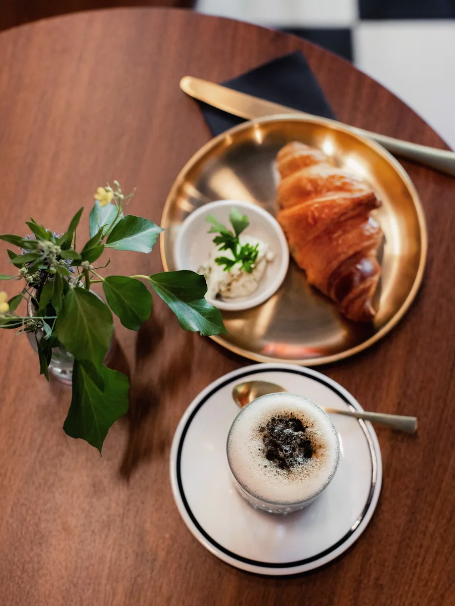 Croissant mit Aufstrich und Kaffee auf einem Holztisch